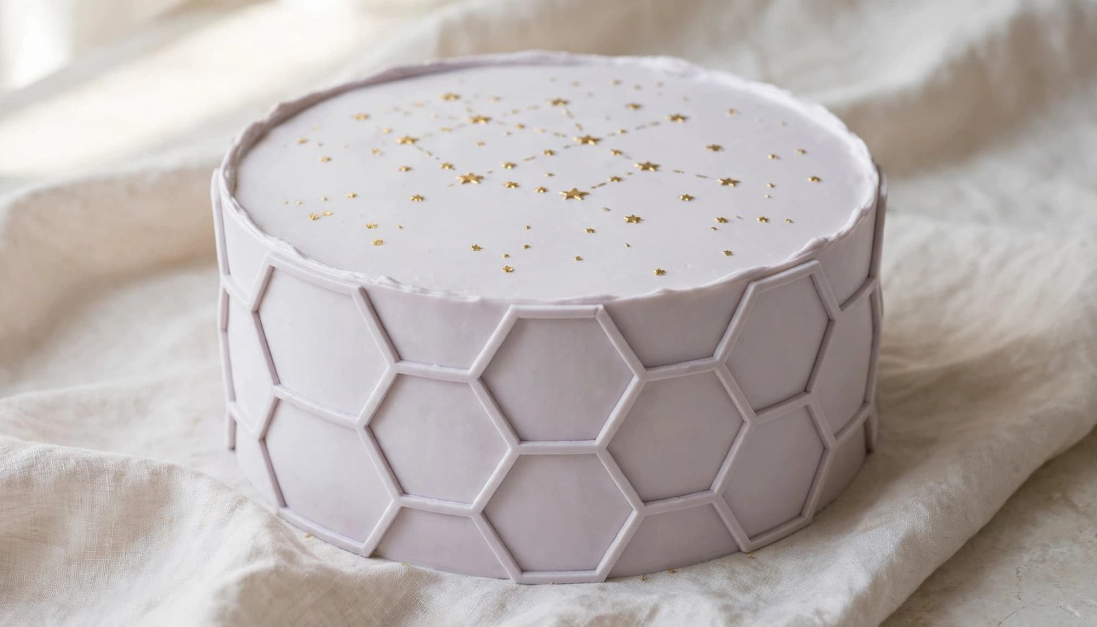 Pale lavender birthday cake with a hexagon design and gold star accents.